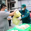 Lực lượng chức năng phường 12, quận 3 hỗ trợ người dân mua hàng hóa, thực phẩm các loại và trứng tại điểm xe bán hàng lưu động của Sở Công thương thành phố. (Ảnh: Thanh Vũ/TTXVN)
