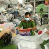 Lực lượng chức năng kiểm đếm các sản phẩm quần áo, túi sách không rõ nguồn gốc, nhập lậu tại cơ sở kinh doanh Trần Lan. (Ảnh: TTXVN phát)