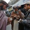 Người dân Afghanistan đổi tiền đôla Mỹ sang đồng nội tệ tại điểm giao dịch ngoại hối ở một khu chợ của Kabul. (Ảnh: AFP/TTXVN)