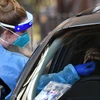 Nhân viên y tế lấy mẫu xét nghiệm COVID-19 cho người dân tại một điểm xét nghiệm di động ở Sydney, Australia. (Ảnh: AFP/TTXVN)