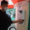 Học sinh lớp 8, 9 trường Trung học cơ sở Hoàng Sa (quận Thọ Quang) đo thân nhiệt và rửa tay bằng nước sát khuẩn tại cổng trường. (Ảnh: Văn Dũng/TTXVN)
