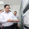 Thủ tướng Phạm Minh Chính xem quy trình bảo quản mẫu hài cốt liệt sỹ. (Ảnh: Dương Giang/TTXVN) 