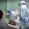 Nhân viên y tế lấy mẫu xét nghiệm COVID-19 cho người dân tại Bình Nhưỡng, Triều Tiên, ngày 10/6/2022. (Ảnh: AFP/TTXVN)
