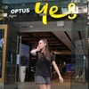 Một phụ nữ sử dụng điện thoại di động khi đi ngang qua cửa hàng Optus ở Sydney, Australia. (Nguồn: Reuters)