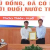 Trao thư khen của Chủ tịch nước Nguyễn Xuân Phúc cho anh Tô Vũ Đồng. (Ảnh: Tường Vi/TTXVN)