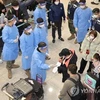 Nhân viên kiểm dịch mặc áo choàng xanh hướng dẫn du khách đến từ Trung Quốc làm xét nghiệm PCR tại Sân bay Quốc tế Incheon, phía Tây Seoul, ngày 2/1/2023. (Nguồn: Yonhap)