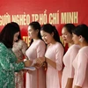 Bà Vũ Tú Oanh, Tham tán thường trực cộng đồng Đại sứ quán Việt Nam tại Lào trao tiền hỗ trợ cho giáo viên Trường Song ngữ Lào - Việt Nam Nguyễn Du. (Ảnh: Phạm Kiên/TTXVN)
