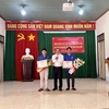 Chủ tịch UBND thành phố Gia Nghĩa Đỗ Tấn Sương (giữa) trao Giấy khen cho 2 thanh niên dũng cảm cứu người. (Ảnh: TTXVN phát)