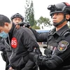 Một nghi phạm lừa đảo bị cảnh sát Trung Quốc áp giải. (Ảnh: China Daily) 
