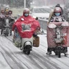 Người dân di chuyển trên đường phố trong thời tiết giá lạnh tại Hoài An, tỉnh Giang Tô, Trung Quốc. (Ảnh: AFP/TTXVN)
