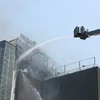 Lực lượng PCCC phải dùng thang cẩu để dập đám cháy trên nhà cao tầng ở ngã bảy Ô Chợ Dừa, quận Đống Đa, Hà Nội sáng 12/3. (Ảnh: Hoàng Hiếu/TTXVN)