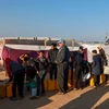 Người Palestine xếp hàng lấy nước sinh hoạt tại khu lều tạm ở Dải Gaza, ngày 16/1/2024. (Ảnh: AFP/TTXVN)