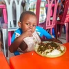 Một em bé mồ côi thưởng thức bữa ăn với ấu trùng mọt cọ. (Nguồn: Farms for Orphans)