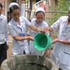 Nhân viên y tế xử lý giếng nước bằng hóa chất khử khuẩn tại vùng "rốn lũ" của tỉnh Quảng Nam. (Ảnh: Hữu Trung/TTXVN)