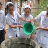 Nhân viên y tế xử lý giếng nước bằng hóa chất khử khuẩn tại vùng lũ của tỉnh Quảng Nam. (Ảnh: Hữu Trung/TTXVN)