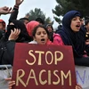 Bé gái cầm tấm biểu ngữ kêu gọi chấm dứt việc phân biệt chủng tộc với người nhập cư. (Ảnh: AFP)