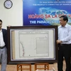 Anh Trần Thắng (bên trái) trao tặng tấm bản đồ Partie de la Cochinchine anh sưu tập được cho ông Võ Ngọc Đồng. Chủ tịch Ủy ban Nhân dân huyện Hoàng Sa. (Ảnh: Lê Lâm/Vietnam+)