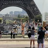 Khách du lịch bên Tháp Eiffel ở Paris (Pháp). (Nguồn: AFP/TTXVN)