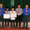 Trao bằng khen của Tỉnh đoàn và tiền thưởng cho hai em học học sinh Nguyễn Văn Chương và học sinh Nguyễn Phi Anh. (Ảnh: Phan Quân/TTXVN) 