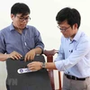 Thầy Tôn Thất Trường Nam (bên trái) và thầy Trần Quốc Lâm giới thiệu về máy phát hiện gian lận thi cử. (Ảnh: Phạm Cường/TTXVN) 