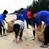 Lực lượng đoàn viên, thanh niên thu gom rác trên bãi biển. (Ảnh: Công Tường/TTXVN)