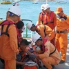 Các nhân viên của Trung tâm tìm kiếm cứu nạn hàng hải Việt Nam khu vực IV kiểm tra sức khỏe của nạn nhân trước khi đưa lên đất liền. (Ảnh: Phan Sáu/TTXVN)
