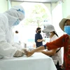 Nhân viên y tế lấy mẫu xét nghiệm nhanh cho người về từ Đà Nẵng. (Ảnh: Minh Quyết/TTXVN)