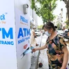 Người dân đến nhận khẩu trang từ cây ATM phát khẩu trang miễn phí trên phố Lạc Trung, Hà Nội. (Ảnh: Thành Đạt/TTXVN)