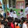Các em học sinh nhóm thiện nguyện Fly to Sky mang áo ấm đến cho trẻ em làng Đê Kôn. (Ảnh: Hồng Điệp/TTXVN) 