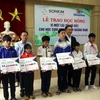 Ông Lê Văn Nhi, Tổng Biên tập Báo Quảng Nam cùng lãnh đạo Công ty SonKim Land trao học bổng cho các em học sinh. (Ảnh: Trịnh Bang Nhiệm/TTXVN)