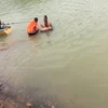 Lực lượng chức năng phối hợp với người dân vớt thi thể nam thanh niên bị đuối nước. (Ảnh: TTXVN phát)