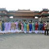 Du khách mặc áo dài truyền thống, đeo khẩu trang phòng dịch chụp ảnh trước cửa Ngọ Môn, Kinh thành Huế. (Ảnh: Đỗ Trưởng/TTXVN)