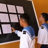  Hai chiến sỹ trẻ lần đầu tiên được đi bầu, theo dõi danh sách cử tri được niêm yết tại Ủy ban Nhân dân xã Song Tử Tây (huyện Trường Sa, tỉnh Khánh Hoà). (Ảnh: Sỹ Tuyên/TTXVN)