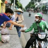 Người dân nhận suất ăn miễn phí từ nhân viên nhà hàng Bò tơ Năm Sánh (quận Gò Vấp, Thành phố Hồ Chí Minh). (Ảnh: Hồng Giang/TTXVN) 