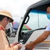Cảnh sát giao thông kiểm tra giấy tờ của một phương tiện chở hàng hóa ngay tại chốt kiểm soát dịch COVID-19. (Ảnh: Minh Sơn/Vietnam+) 