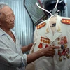 Đại tá Bành Văn Đởm bên những huân, huy chương được tặng thưởng. (Ảnh: TTXVN phát)