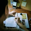 Em Cẩm Ly, học sinh lớp 7 trường THCS Lê Bình (quận Cái Răng, thành phố Cần Thơ) ghi chép lại bài trong thời gian lên lớp trực tuyến. (Ảnh: Thanh Liêm/TTXVN)