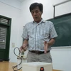 Thầy Nguyễn Văn Thịnh thuyết minh về nguyên lý hoạt động của máy nghiền bi trục đứng. (Ảnh: Văn Dũng/TTXVN)