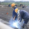 Các công nhân vẫn tiếp tục thi công và đón Tết Dương lịch 2022 ngay trên công trường Cầu Vĩnh Tuy 2. (Ảnh: Hoàng Hiếu/TTXVN) 