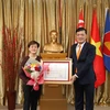 Đại sứ Mai Phước Dũng thay mặt Chủ tịch nước trao Huân chương hữu nghị cho bà Catherin Wong. (Ảnh: Lê Ngọc Dương/TTXVN)