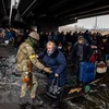 Binh sỹ Ukraine hỗ trợ người sơ tán khỏi thành phố Irpin, phía Tây Bắc thủ đô Kiev. (Ảnh: AFP/TTXVN)