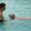 Huấn luyện viên hướng dẫn học sinh kỹ năng bơi cơ bản. (Ảnh: Thanh Tùng/TTXVN)