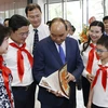 Chủ tịch nước Nguyễn Xuân Phúc và các đại biểu tham quan trưng bày Dấu ấn 65 năm Nhà xuất bản Kim Đồng. (Ảnh: Thống Nhất/TTXVN) 
