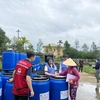 Hỗ trợ thùng nhựa cho các gia đình có nguy cơ chịu ngập lụt do mưa bão ở Thừa Thiên-Huế. (Ảnh: TTXVN phát)
