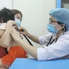 Bác sỹ Bệnh viện Bệnh nhiệt đới Trung ương khám cho bệnh nhi xuất hiện triệu chứng cúm A. (Ảnh: Minh Quyết/TTXVN) 