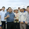Thủ tướng Phạm Minh Chính nói chuyện với công nhân xây dựng dự án tuyến đường Đông-Tây giai đoạn 1 đoạn từ thành phố Tam Điệp đến huyện Nho Quan. (Ảnh: Dương Giang/TTXVN) 