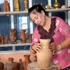 Nghệ nhân làng gốm Bình Đức Nguyễn Thị Mai hoàn thiện sản phẩm gốm Chăm đặc trưng. (Ảnh: Nguyễn Thanh/TTXVN)