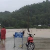 Lực lượng chức năng huyện Đồng Xuân, tỉnh Phú Yên gắn biển cảnh báo và cử lực lượng chức năng chốt chặn tại một tuyến đường bị ngập trong nước lũ. (Ảnh: TTXVN phát)
