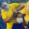 Anh Ngô Trọng Giáp cắt tỉa, căn chỉnh cẩn thận từng mái tóc cho bệnh nhân đang điều trị tại Bệnh viện Đa khoa huyện Triệu Phong. (Ảnh: TTXVN phát)