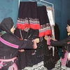 Các nghệ nhân giới thiệu về các loại trang phục truyền thống của dân tộc Dao. (Ảnh: Hữu Quyết/TTXVN) 